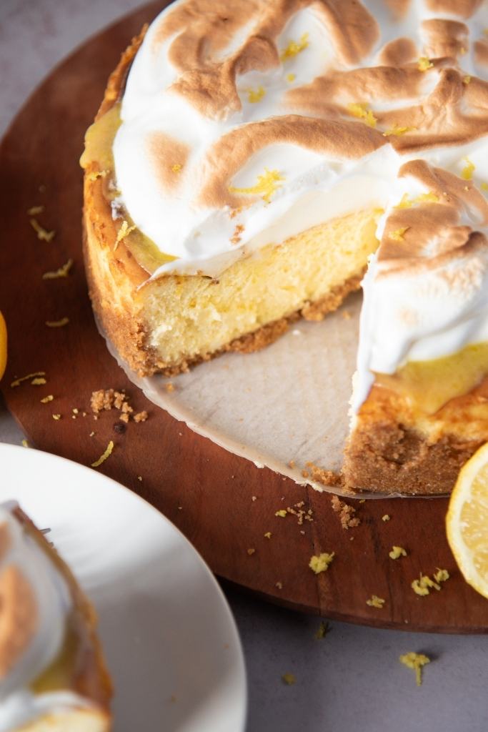a lemon meringue cheesecake that has a piece taken out of it