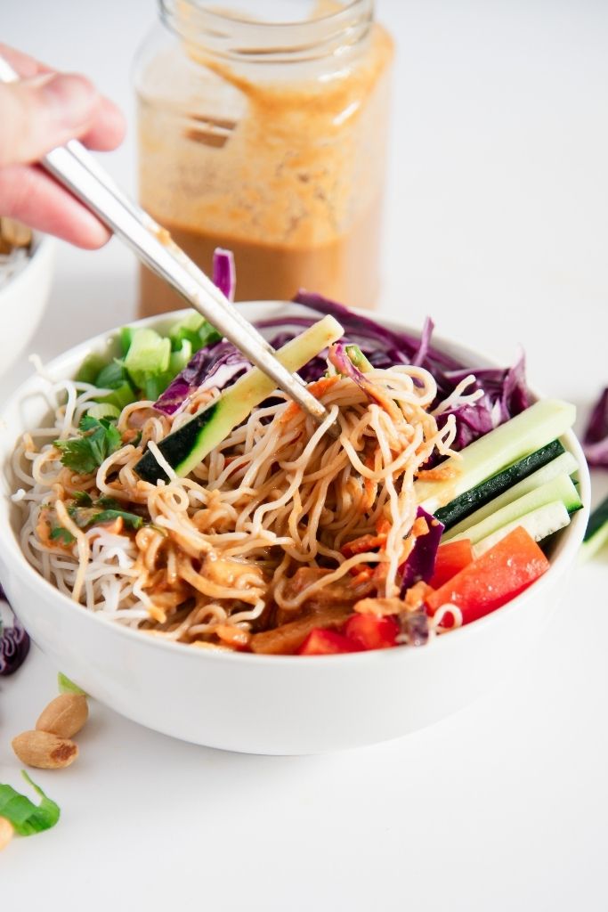 a bite of spring roll salad bring held over a bowl of salad 