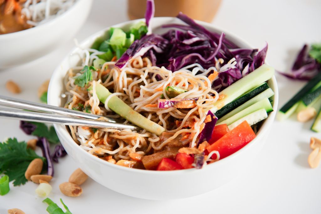a mixed bowl of spring roll salad with chopsticks stuck in it 