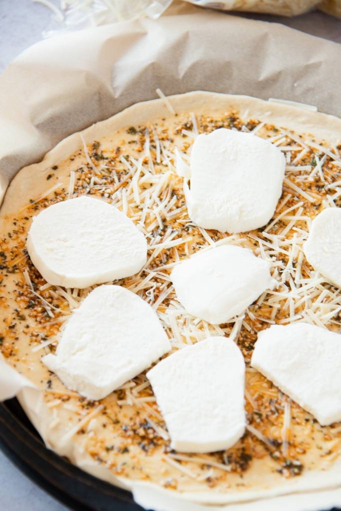 an unbaked pizza crust with oil and cheese on it 