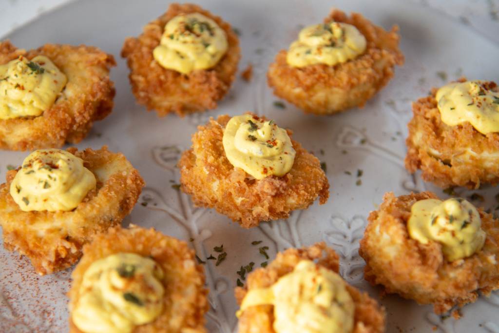 a plate of deep fried deviled eggs with seasoning sprinkled around them