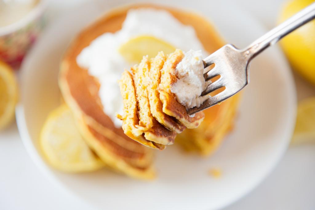 a forkful of pancakes being held over a plate of pancakes 