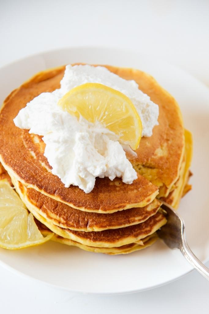a close up of a stack of pancakes, that is being cut into with a fork