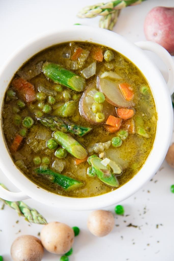 a close up of a bowl of springtime soup, you can also see some fresh veggies next to the bowl