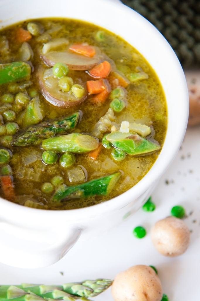 a cut off picture of a bowl of soup with fresh veggies around it 