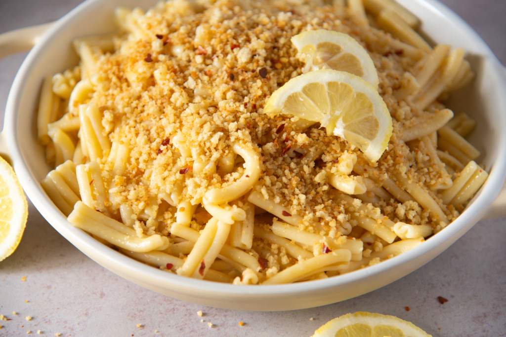 a dish of lemon pasta with breadcrumbs and lemon slices on top