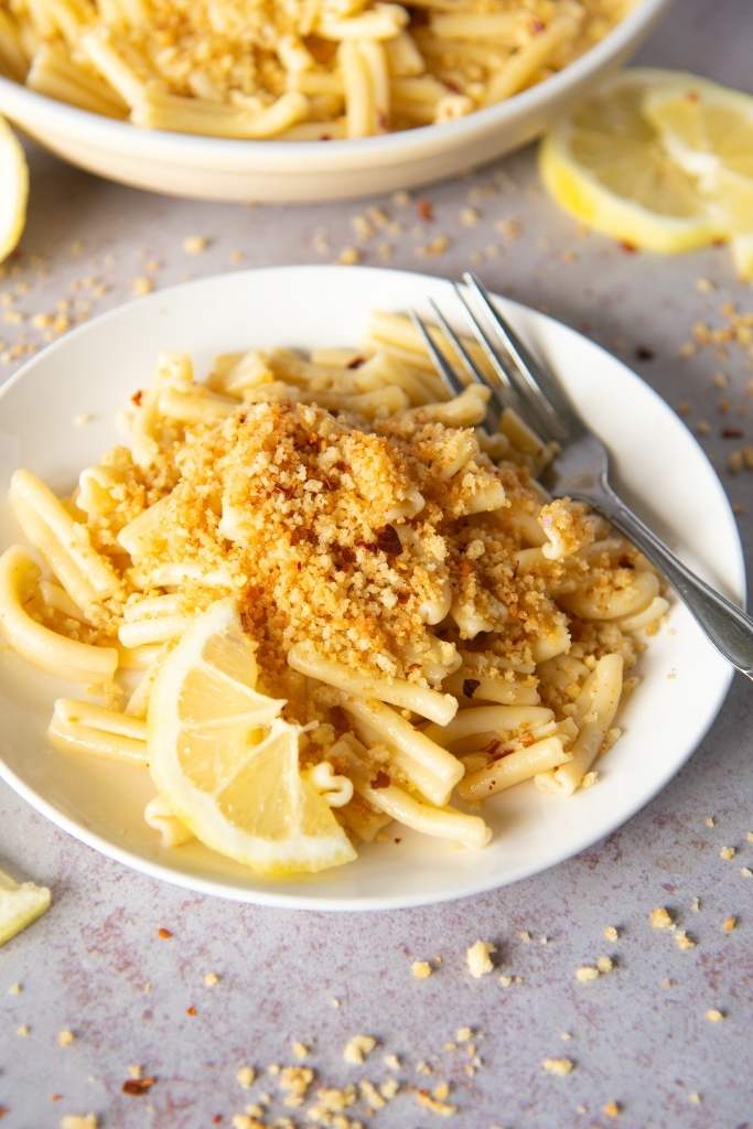 a plate of lemon pasta there is a fork and lemon slices on the plate as well