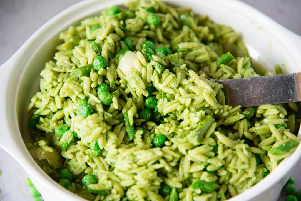 a bowl of pasta salad with a spoon in it 