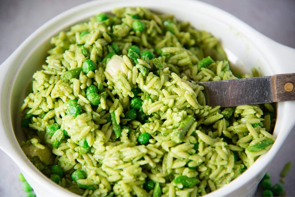a bowl of orzo pasta salad with a spoon in it 