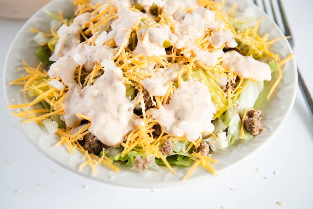 a close up of a bowl of salad with fork next to it
