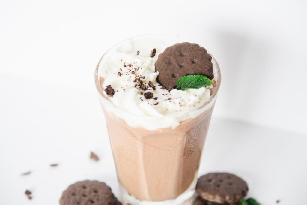 a close up of a shake with cookies and mint leaves around it 