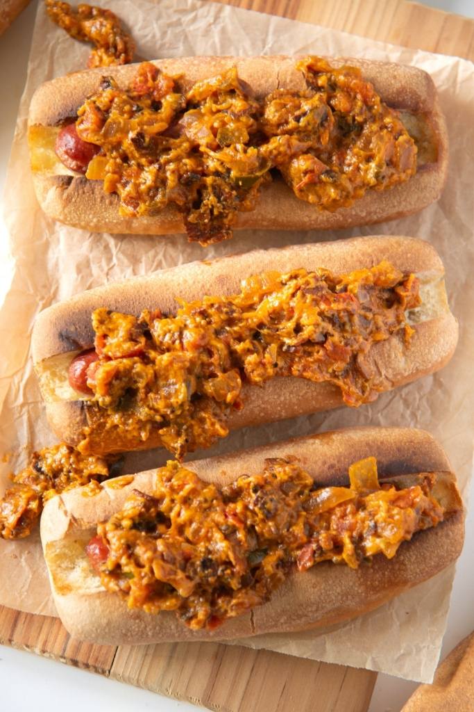 an overhead shot of three hot dogs on a wooden serving tray.