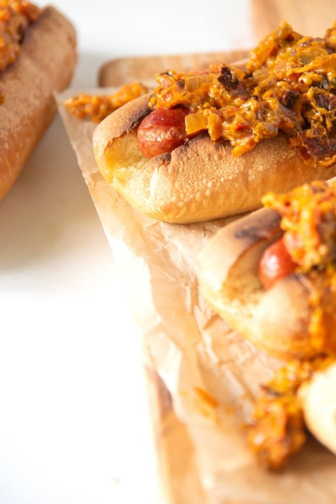 a close up of a hot dog on a wooden serving tray, you can see other hot dogs next to it as well