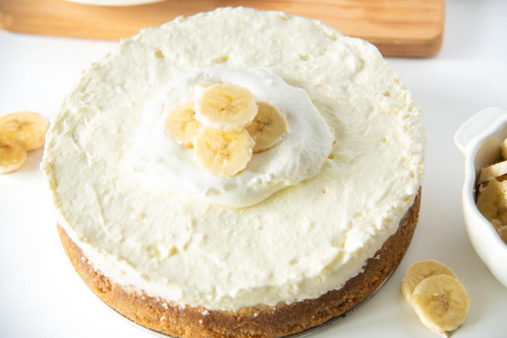 a banana pudding cheesecake with a dish of bananas and come banana slices around it 