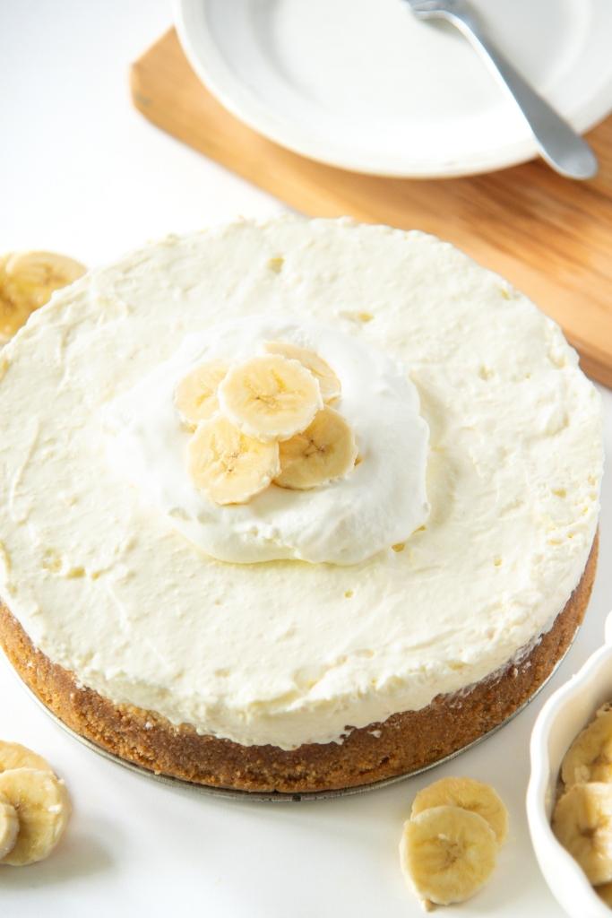 a close up of a banana cheesecake with whipped cream and banana slices on it 