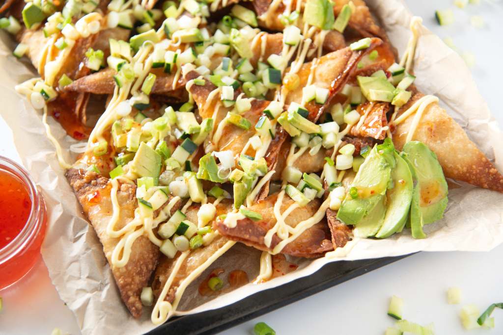 a tray of rangoon nachos, there is some extra sliced avocado on the edge of the tray 