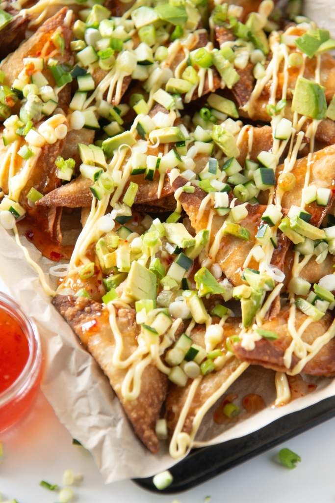 a close up of a tray of rangoon nachos, you can see part of a dish of sweet chili sauce next to the tray 