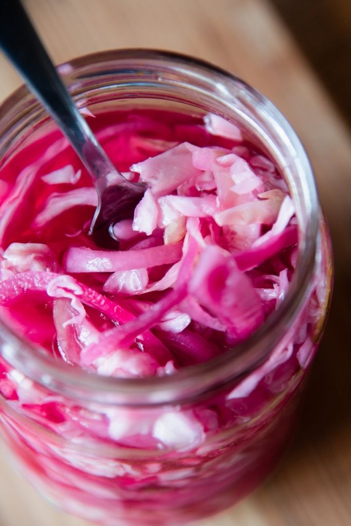 a jar of pickled cabbage with a fork in it 