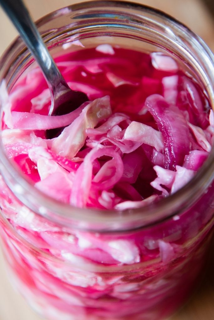 a close up of a jar of pickled cabbage and onions with a fork stuck in it 