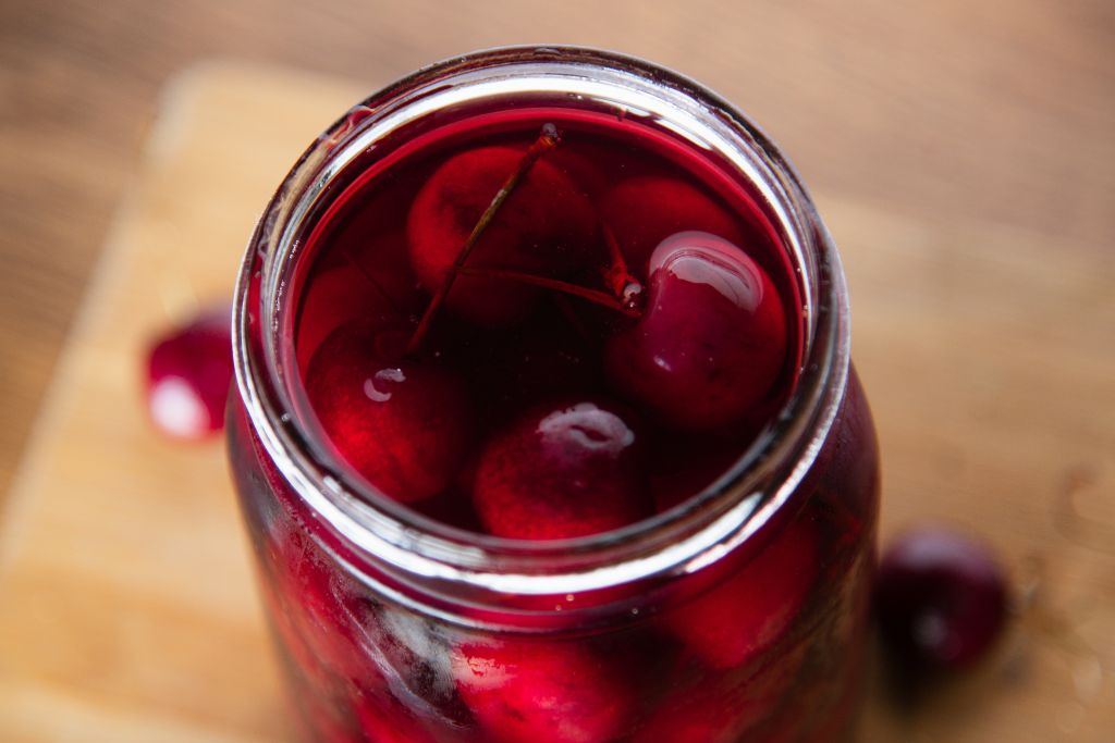 a close up of an open jar of pickled cherries 