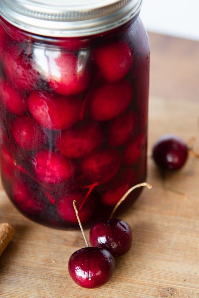 a close up of a jar of pickled cherries 