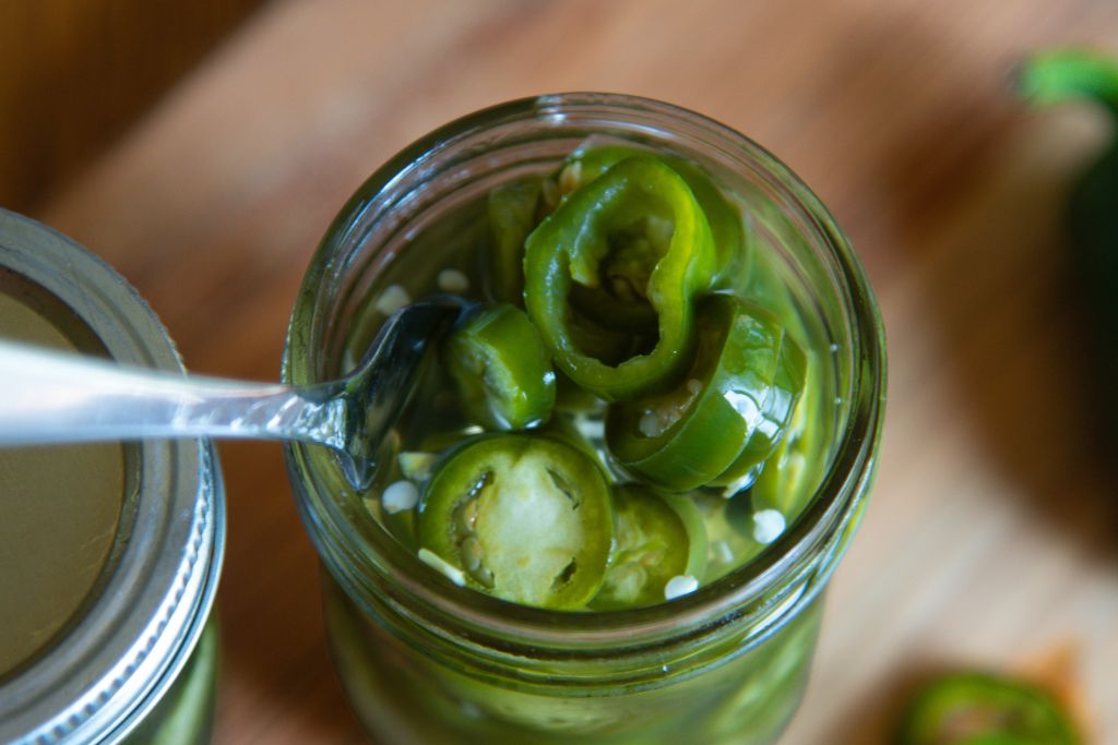 a close up of a jar of jalapenos with a fork in it.