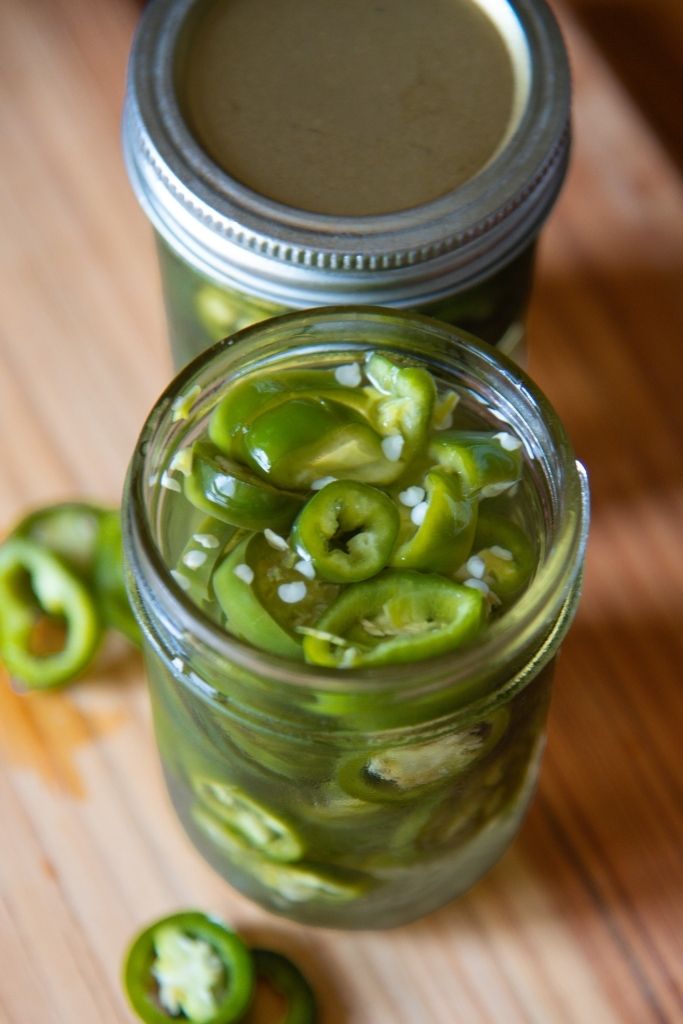 a close up an open jar of jalapenos, there is another jar behind it.