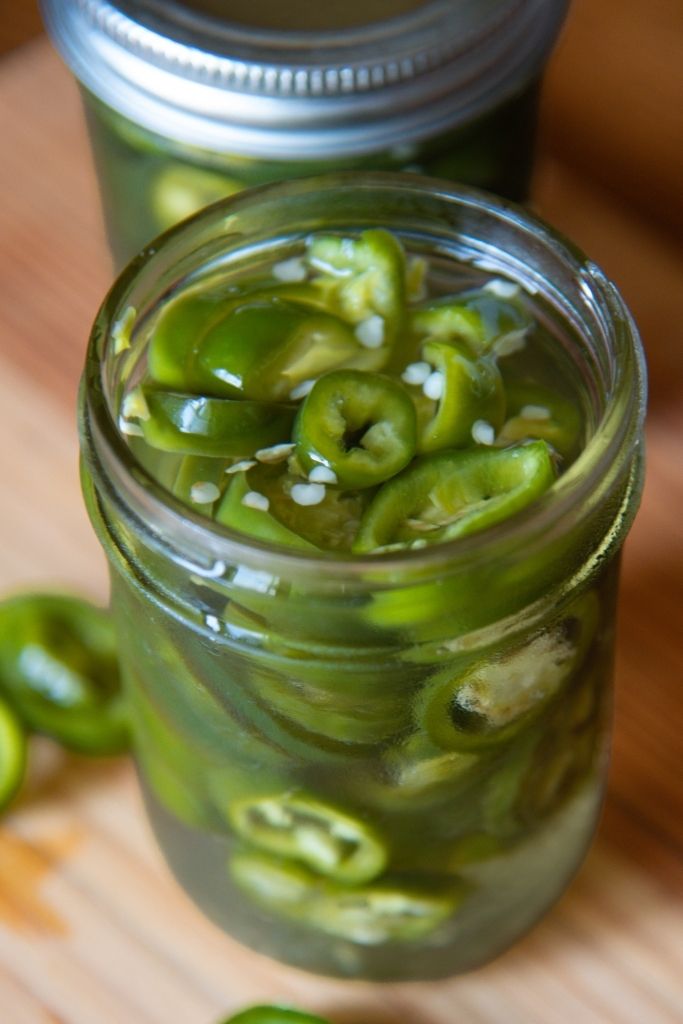 a close up of an open jar of pickled jalapenos