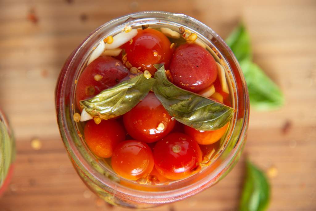 a close up of an open jar of pickled tomatoes 