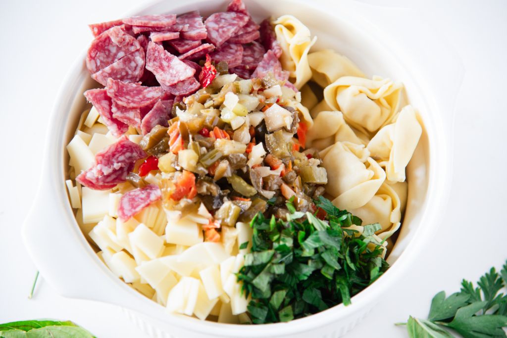 a bowl of tortellini with the salad ingredients on top of it 