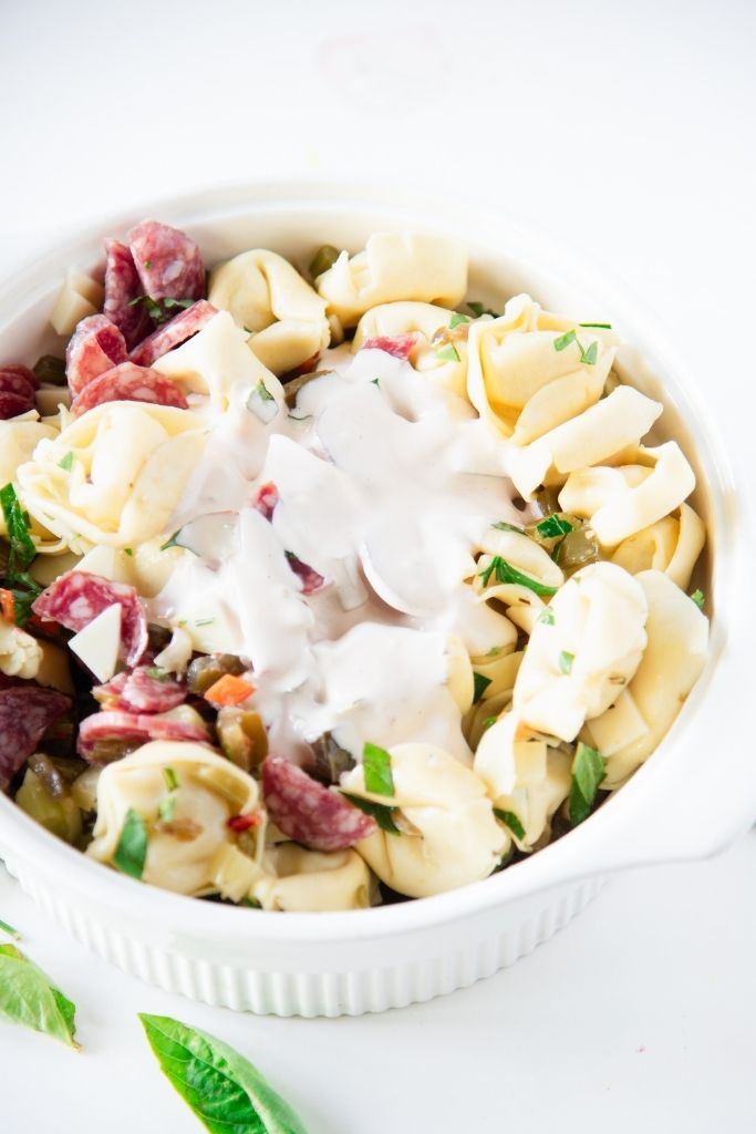 a bowl of pasta salad with dressing poured on top of it 