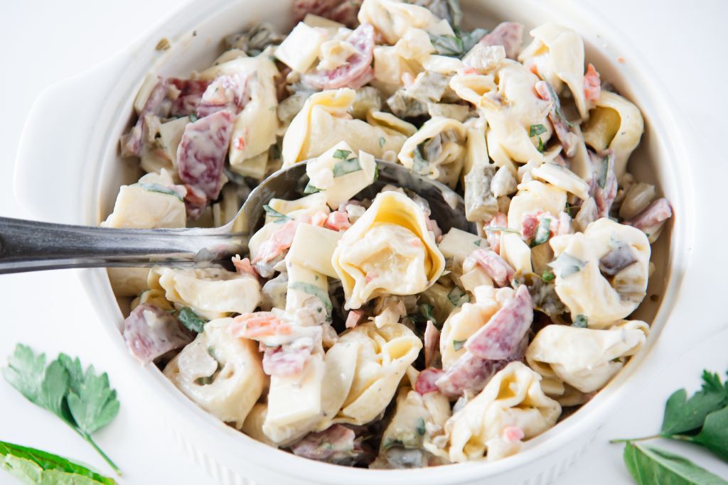a bowl of pasta salad with a serving spoon in it 