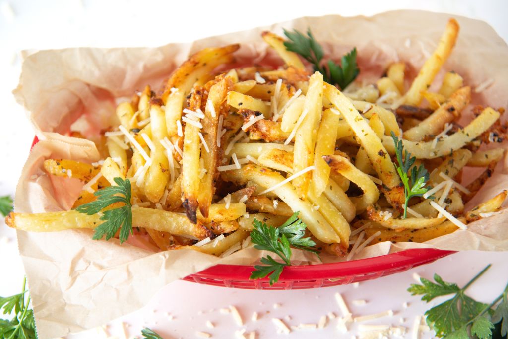 a basket of french fries with cheese and fresh parsley sprinkled over them