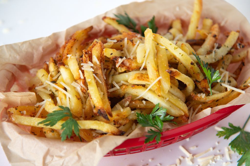 a basket of French fries with parsley sprinkled on it