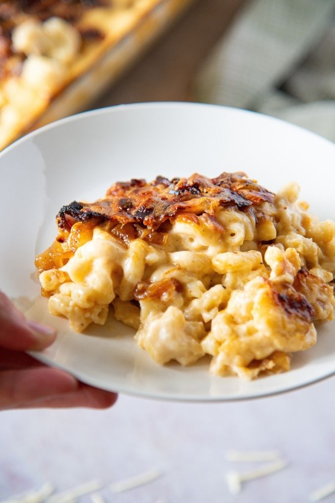 someone holding a plate of mac n cheese