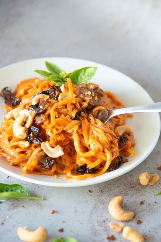 a plate of red curry noodles with a fork stuck in it