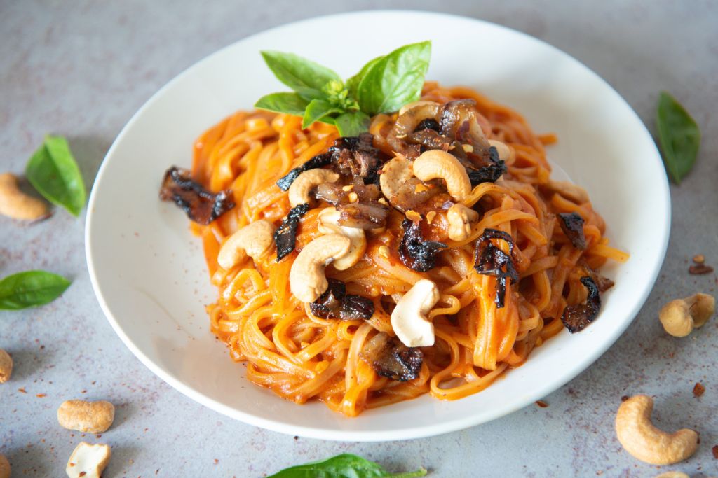 a plate of red curry noodles with fresh basil on top
